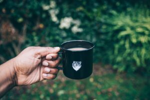Hand holding a cup of coffee outdoors.